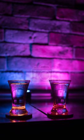 Téléchargez les photos : Verre de vodka froide sur fond sombre dans la lumière au néon ou verres de vodka russe sur fond de bar. focus sélectif - en image libre de droit