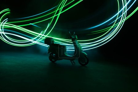 Foto de Silueta de scooter miniatura de pie sobre fondo oscuro con luz. Enfoque selectivo - Imagen libre de derechos