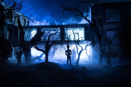 Téléchargez les photos : Silhouette de personne debout dans la forêt sombre avec de la lumière. Horreur concept d'Halloween. étrange silhouette au bâtiment abandonné - en image libre de droit