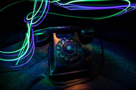 Foto de Viejo teléfono negro sobre tabla de madera vieja con arte fondo oscuro con niebla y luz tonificada. espacio vacío. Enfoque selectivo - Imagen libre de derechos