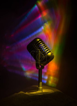 Foto de Micrófono para sonido, música, karaoke en estudio de audio o escenario. Tecnología de micrófonos. Equipo de transmisión de voz. Micrófono en habitación oscura en la mesa con contraluz. Enfoque selectivo - Imagen libre de derechos