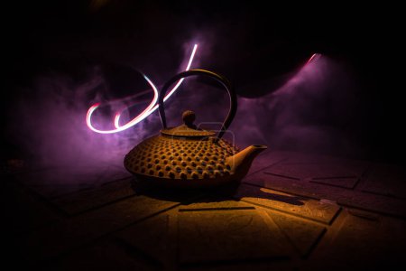 Photo for Arabian tea kettle on a stone surface on dark background with lights and smoke. Eastern tea concept. Selective focus. - Royalty Free Image