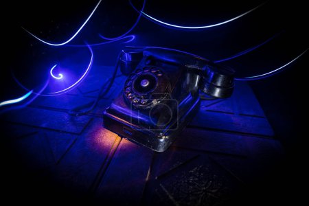 Téléchargez les photos : Vieux téléphone noir sur vieille planche de bois avec fond sombre art avec brouillard et lumière tonique. espace vide. Concentration sélective - en image libre de droit