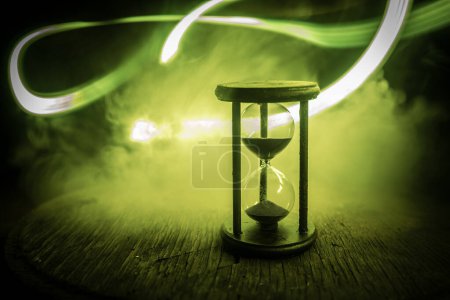 Photo for Hourglass as time passing concept for business deadline, urgency and running out of time. Sandglass, egg timer on dark background showing the last second or last minute or time out. With copy space. - Royalty Free Image