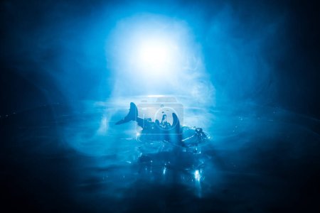Abstraktes Konzept. Fische (Haie) Silhouette springen auf dem Wasser in der Nacht. Wasser plätschert vor dunklem, nebligem Hintergrund. Selektiver Fokus.