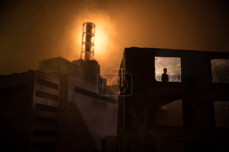 Creative artwork decoration. Chernobyl nuclear power plant at night. Layout of abandoned Chernobyl station after nuclear reactor explosion. Man silhouette in window. Selective focus