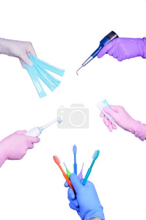 Téléchargez les photos : Beaucoup de mains dans des gants de couleur médicale tient une brosse à dents, pâte à dents, brosses interdentaires, jet de sable dentaire et d'autres. Concept d'hygiène dentaire. - en image libre de droit
