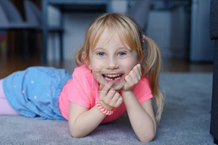 Photo for Six year old smiling happy girl holding a first fallen tooth and looking at him. - Royalty Free Image