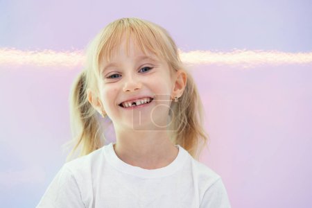 Photo for A happy six-year-old blondy girl smiles widely after her front baby tooth fell out. - Royalty Free Image