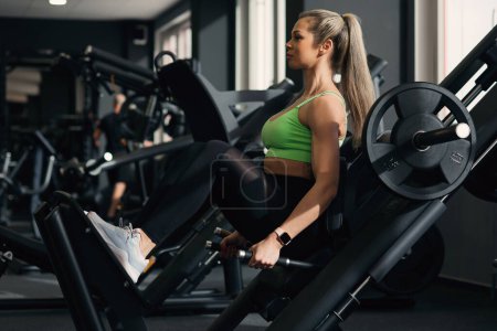 Téléchargez les photos : Femme de remise en forme faisant un squat profond sur la machine à pirater dans la salle de gym moderne. - en image libre de droit