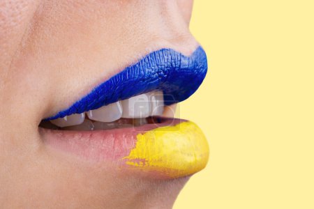 Photo for Close up of beautiful and plump female lips painted in blue and yellow. Lips of unrecognizable woman painted in Ukrainian flag colors. - Royalty Free Image
