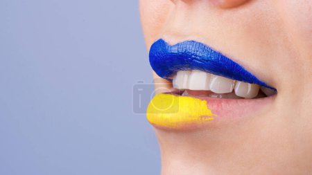 Photo for Close up of beautiful and plump female lips painted in blue and yellow. Lips of unrecognizable woman painted in Ukrainian flag colors. Isolated background - Royalty Free Image