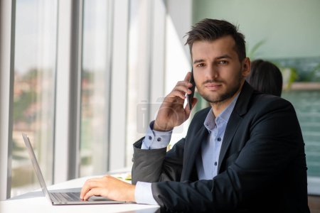 Photo for Young businessman talking on the phone at the office. - Royalty Free Image