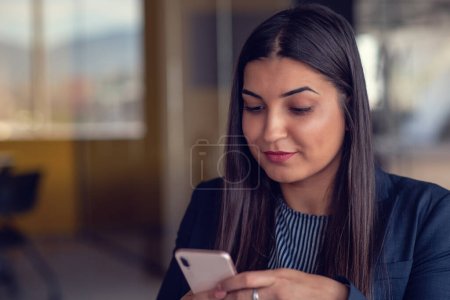 Téléchargez les photos : Femme d'affaires sérieuse parlant sur un téléphone portable au bureau, travaillant à l'ordinateur. - en image libre de droit
