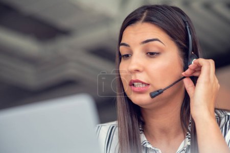 Téléchargez les photos : Jeune opératrice sympathique agent avec écouteurs travaillant dans un centre d'appels - en image libre de droit