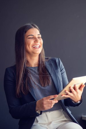 Téléchargez les photos : Jeune gestionnaire attrayant femme travaillant sur tablette numérique tout en se tenant dans le bureau moderne
. - en image libre de droit