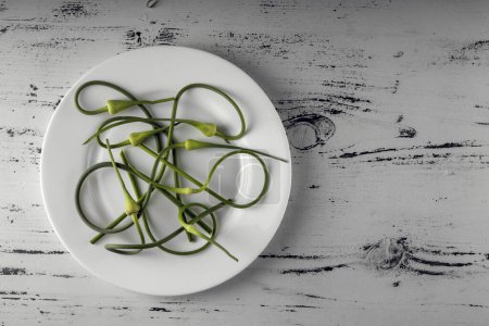 Rustic Wooden Table Setting with Plate of Fresh Garlic Scapes