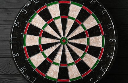 Photo for New classic professional sisal dart board on black wooden background. Close up - Royalty Free Image