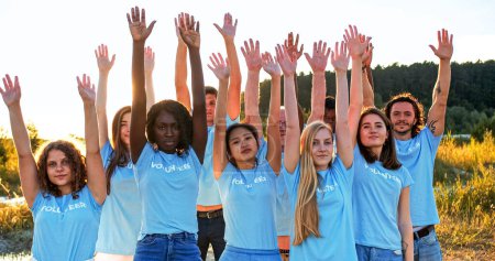 Téléchargez les photos : Des militants multiethniques joyeux levant, levant, levant les mains vers le ciel. Des bénévoles souriants de différents âges regardant la caméra. Amitié, travail d'équipe, esprit d'équipe, concept de coopération. - en image libre de droit