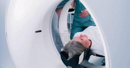 Primer plano de la espalda de la mujer que sale de la cápsula de resonancia magnética. El paciente ha terminado el procedimiento de resonancia magnética. El médico realiza una tomografía computarizada. La hembra se mueve en la cama del escáner de resonancia magnética.