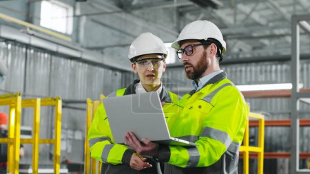 Photo for Main engineer briskly explains plan of action to employee. Bearded man holding notebook and gesturing. Workers in yellow jackets and helmets cooperate at construction site. - Royalty Free Image