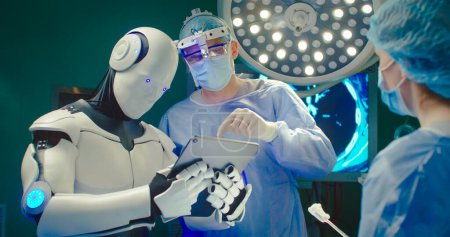 Foto de Robot celebración tableta digital ayuda al médico a realizar la operación quirúrgica en el hospital moderno. Trabajo en equipo de cirujanos médicos profesionales en quirófano. Concepto de medicina moderna. - Imagen libre de derechos