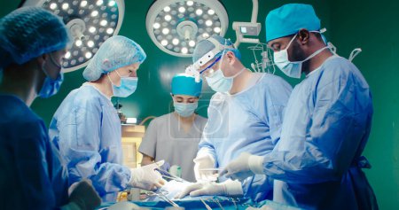 Travailleurs médicaux en masque spécial et gants. Médecins de fond de l'équipement médical dans la salle d'opération. Le docteur tient les ciseaux et termine l'opération. Stagiaire tient patients tube respiratoire.