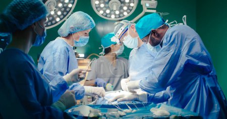 Tir doux. Une assistante tient le tube respiratoire au patient. Les médecins en salopette effectuent une chirurgie. Travailleurs médicaux sur fond d'équipement. Stagiaire mains paire de ciseaux au médecin en jumelles.