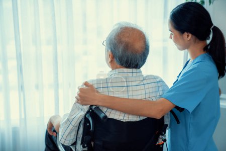 Rear view of a caregiver and her contented senior man gazing out through the window. Elderly health care, nursing homes for the elderly, and pensioner life