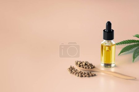 Legalized marijuana concept features with CBD oil extract from marihuana in glass bottle with dropper lid, piles of hemp seeds on empty background. Marijuana products for copyspace and advertising.
