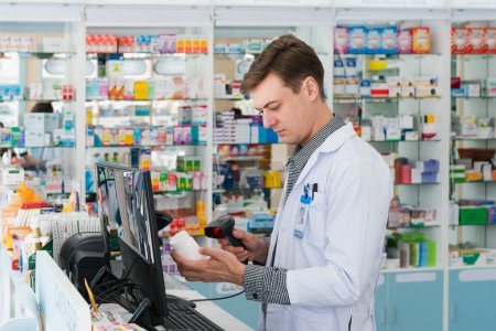 Foto de Retrato de un joven farmacéutico escaneando el código de barras de una maqueta farmacéutica calificada, envase de píldora de medicina o frasco para espacio de copia en la farmacia. - Imagen libre de derechos