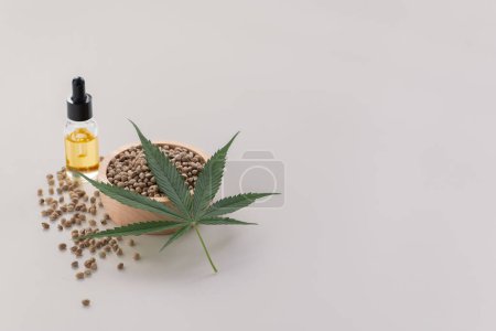 Foto de Concepto de marihuana legalizado con extracto de aceite de CBD de marihuana en botella de vidrio con tapa cuentagotas, montones de semillas de cáñamo sobre fondo vacío. Productos de marihuana para copyspace y publicidad. - Imagen libre de derechos