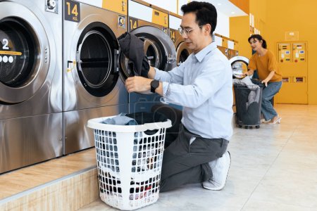 Foto de Gente asiática usando la máquina de lavar monedas calificada en la sala pública para lavar sus paños. Concepto de una máquina de secado y lavandería comercial de autoservicio en una sala pública. - Imagen libre de derechos