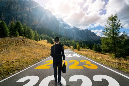 Téléchargez les photos : Le voyage du Nouvel An 2023 et le concept de vision d'avenir. Homme d'affaires voyageant sur la route de l'autoroute menant à la célébration heureuse de la nouvelle année au début de 2021 pour un nouveau départ réussi . - en image libre de droit