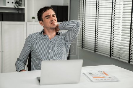 Foto de Competent office worker experiencing fatigue and neck pain. Unhealthy concept for office workers, office syndrome. - Imagen libre de derechos