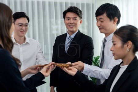 Foto de Closeup hand holding wooden gear by businesspeople wearing suit for harmony synergy in office workplace concept. Group of people hand making chain of gears into collective form for unity symbol. - Imagen libre de derechos