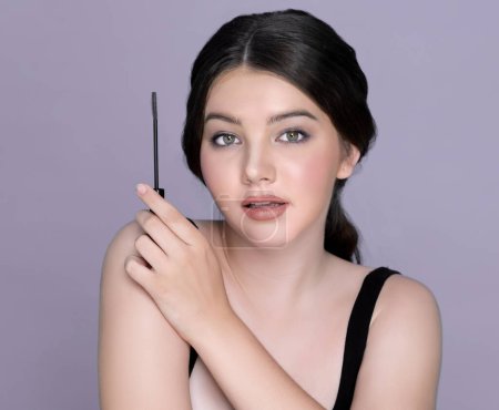 Foto de Closeup portrait of young charming applying makeup eyeshadow on her face with brush, mascara with flawless smooth skin for beauty concept. Luxury cosmetic makeup. - Imagen libre de derechos