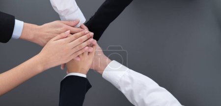 Top view partial hands wearing formal suit joining stack and form circle as symbol of team building, unity and harmony in office workplace. Successful business team of synergy holding hand together.
