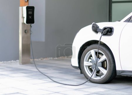 Photo for Progressive concept of EV car and home charging station powered by sustainable and clean energy with zero CO2 emission for green environmental. Charging point at residential area for electric vehicle. - Royalty Free Image