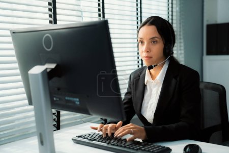 Photo for Competent female operator working on computer and talking with clients. Concept relevant to both call centers and customer service offices. - Royalty Free Image