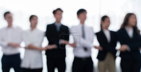 Foto de Blurry image of businesspeople holding their hand in line as to show concept of unity teamwork and harmony in office workplace. Office worker standing in line and join hands as collective from. - Imagen libre de derechos