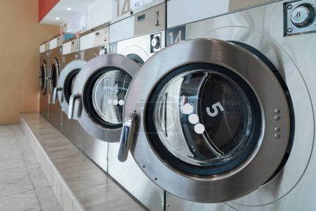 Foto de Una fila de lavadoras de monedas calificadas en una tienda pública. Concepto de una máquina de secado y lavandería comercial de autoservicio en una sala pública. - Imagen libre de derechos