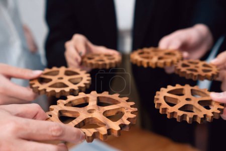 Photo for Closeup hand holding wooden gear by businesspeople wearing suit for harmony synergy in office workplace concept. Group of people hand making chain of gears into collective form for unity symbol. - Royalty Free Image