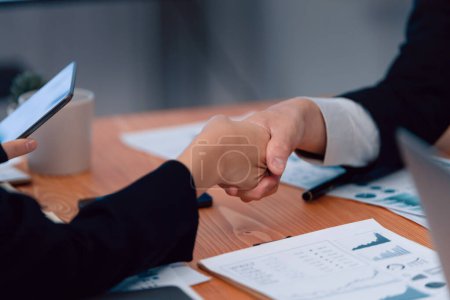 Focus handshake by businessman in formal wear in meeting room after successful agreement or deal. Colleagues shake hands to each other after getting promotion as concept of harmony and unity concept. Poster 647955360