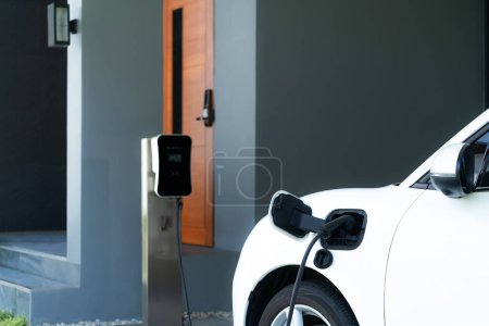 Progressive concept of EV car and home charging station powered by sustainable and clean energy with zero CO2 emission for green environmental. Charging point at residential area for electric vehicle.
