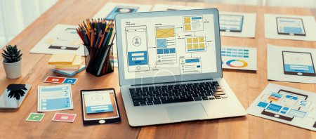 Digitale und papierene Wireframe-Designs für Web- oder mobile App-UI-Displays auf dem Laptop-Computerbildschirm. Panoramaaufnahme des Entwicklerarbeitsplatzes für Brainstorming und Design Application Framework. Prüfen