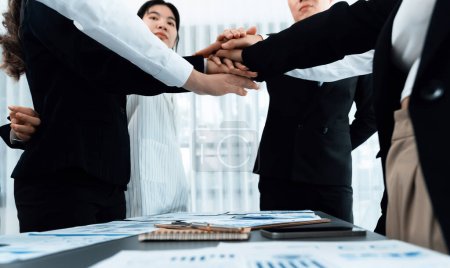 Foto de Closeup business team of suit-clad businessmen and women join hand stack together and form circle. Colleague collaborate and work together to promote harmony and teamwork concept in office workplace. - Imagen libre de derechos