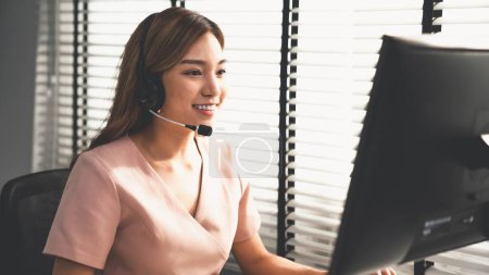 Competent female operator working on computer and while talking with clients. Concept relevant to both call centers and customer service offices.