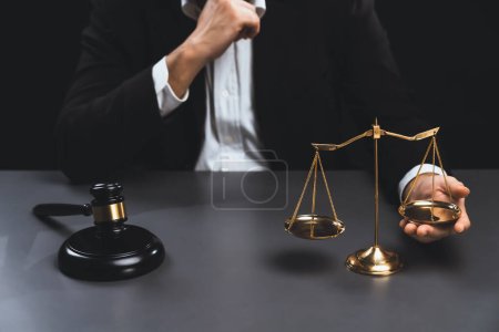 Photo for Focus symbols of justice, gavel hammer and scale balance on blurred background of thoughtful lawyer or judge sitting at his desk for integrity and fairness of the legal system. equility - Royalty Free Image