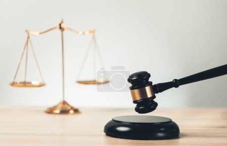 Simbolizando la justicia y la autoridad legal, la balanza de oro equilibrada y el mazo en el escritorio con el libro de leyes en el fondo de la oficina de abogados, que refleja el concepto de igualdad y juicio justo. equilidad